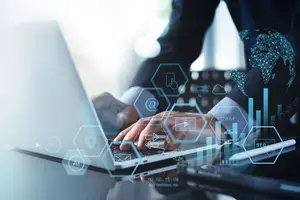 Ein Mann arbeitet am Laptop. Symbile for Digitalisierung im Vordergrund.